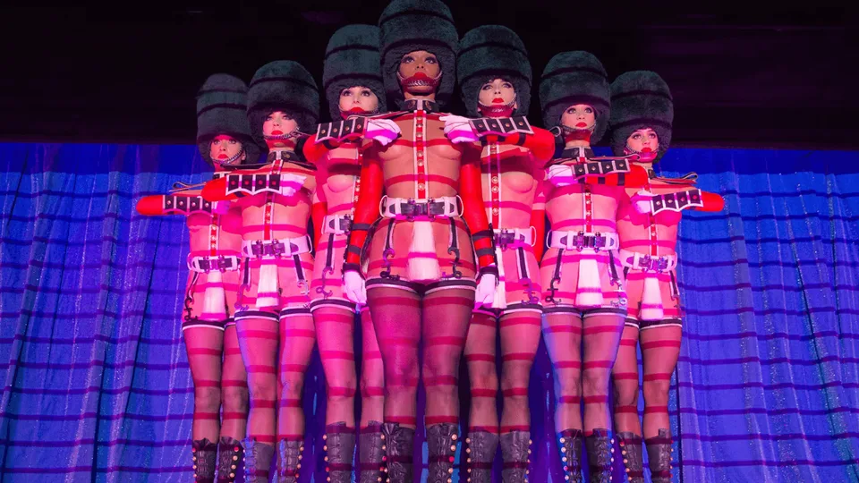 Crazy Horse performers under geometric red and blue stage lighting