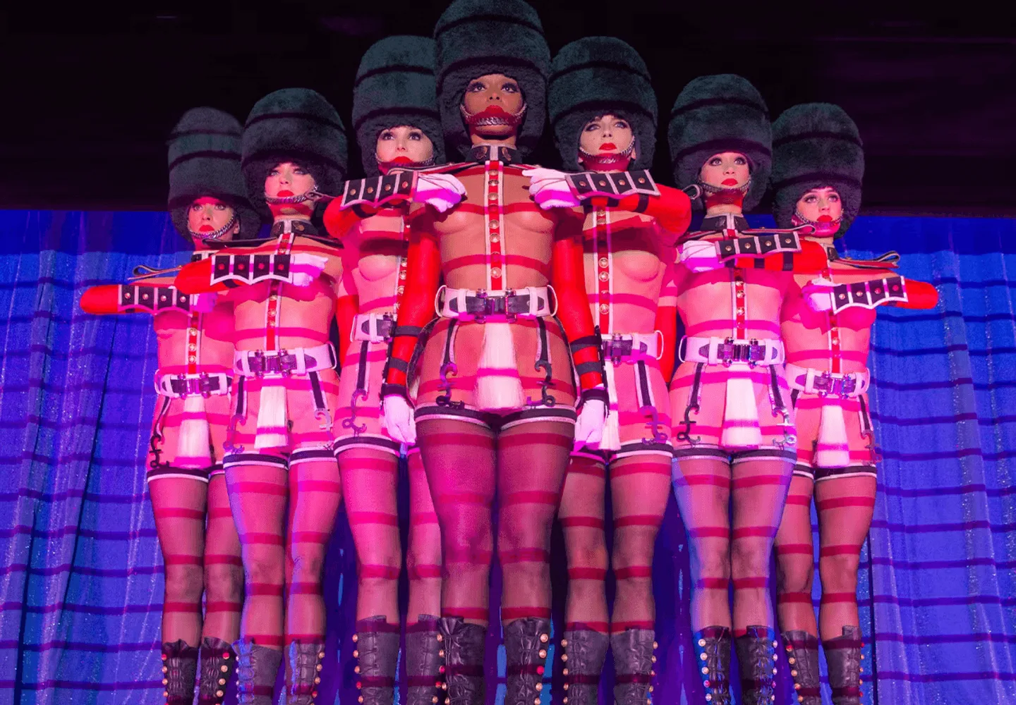 Crazy Horse performers under geometric red and blue stage lighting