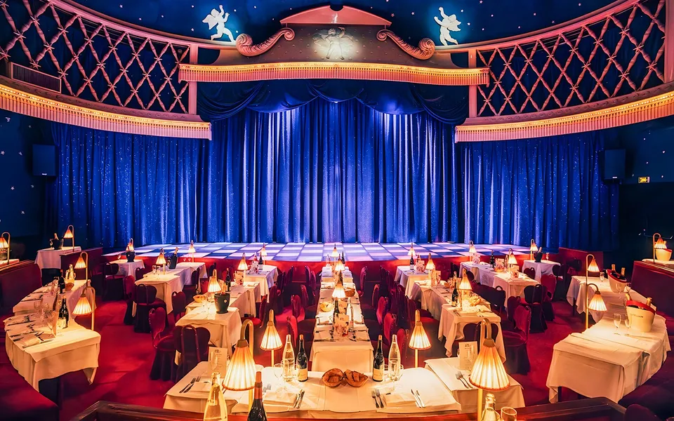 Red dining tables and blue stage curtains at La Nouvelle Eve