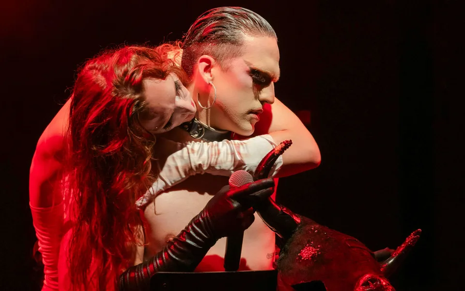 Two Madame Arthur performers under red stage lighting