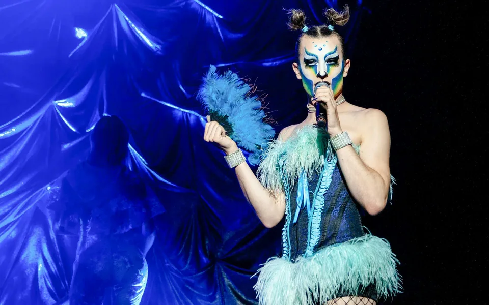 Madame Arthur singer wearing blue feathers at a microphone