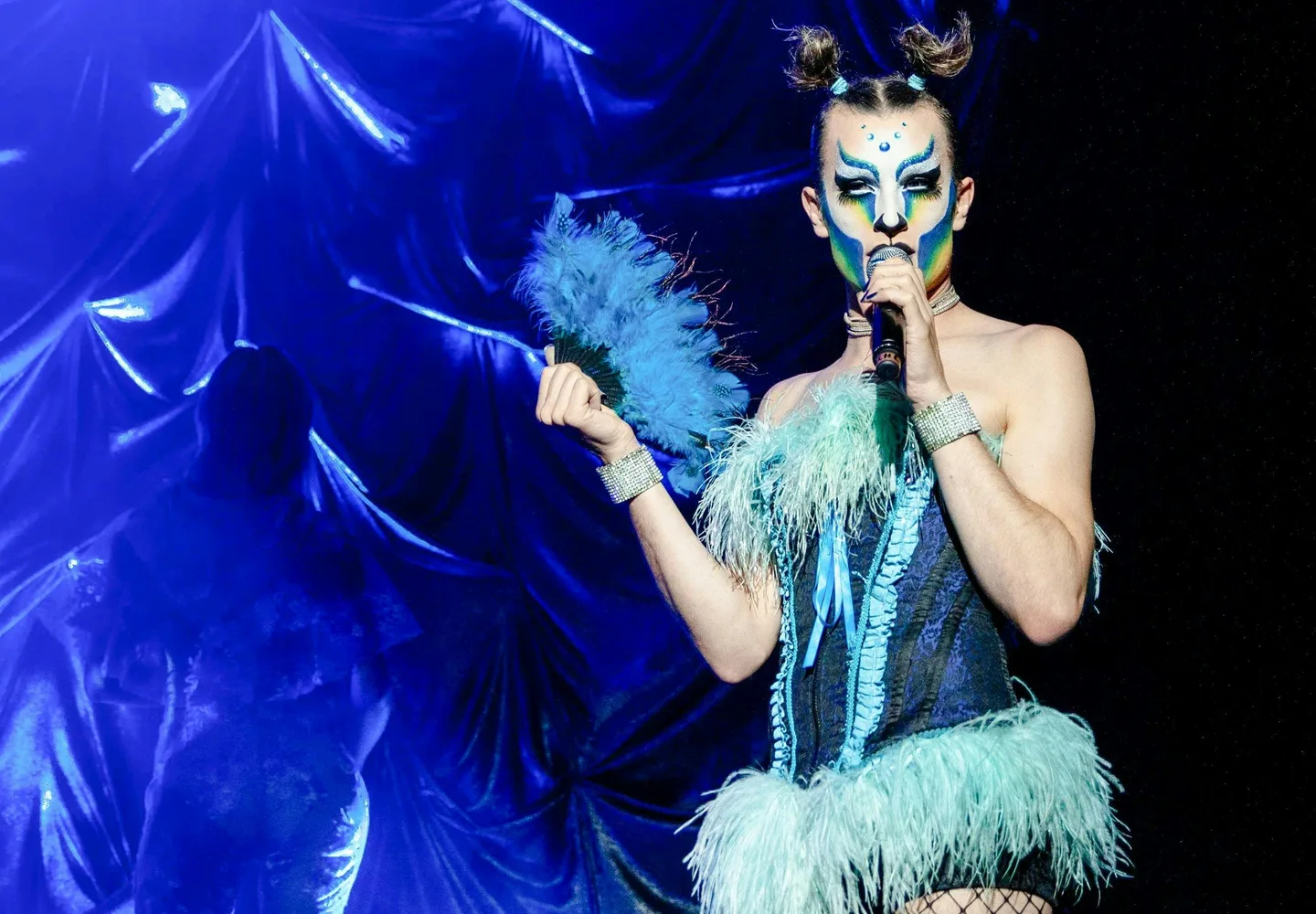Madame Arthur singer wearing blue feathers at a microphone